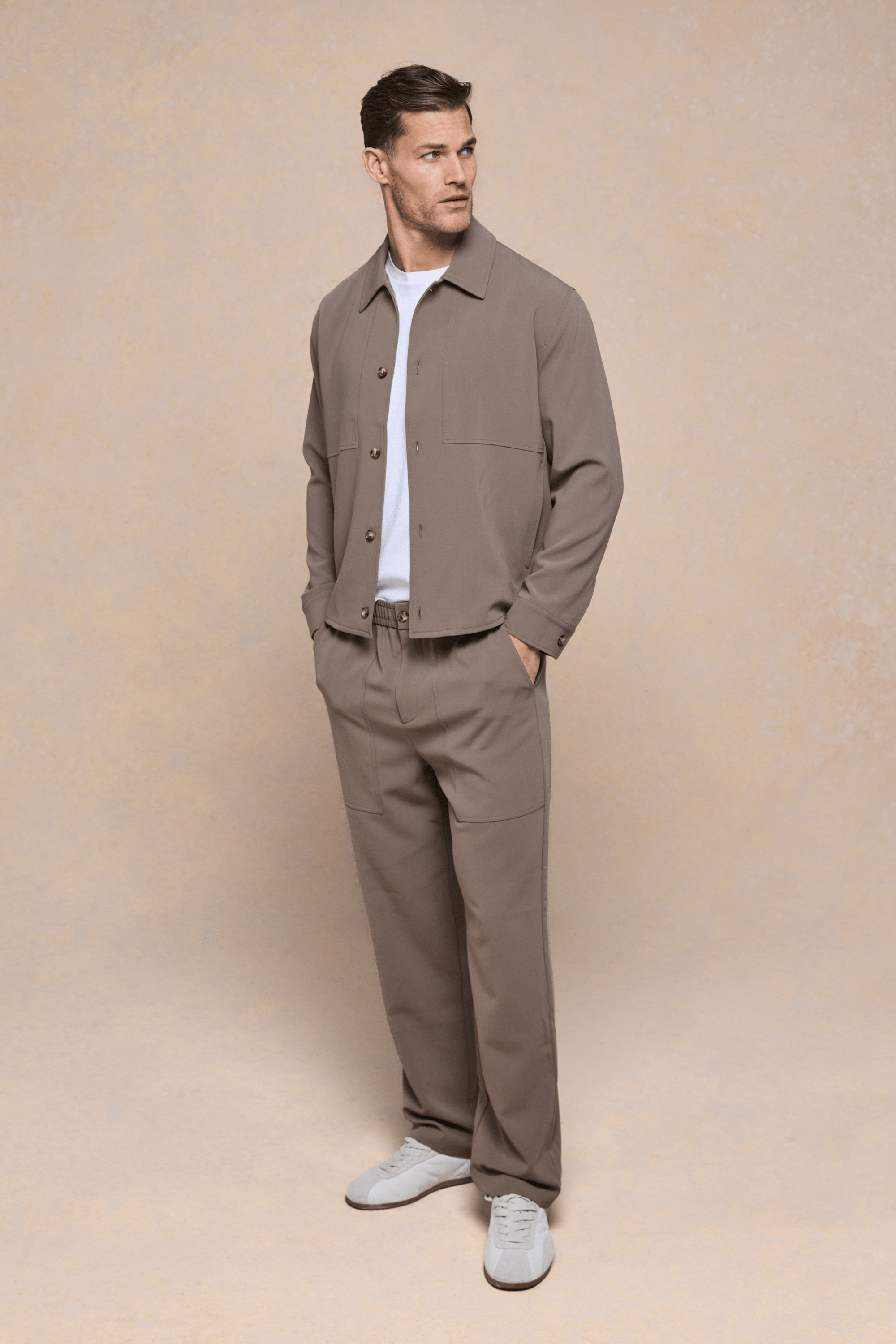 Man in olive Julien Relaxed Panelled Trouser and matching jacket, white t-shirt, and sneakers.