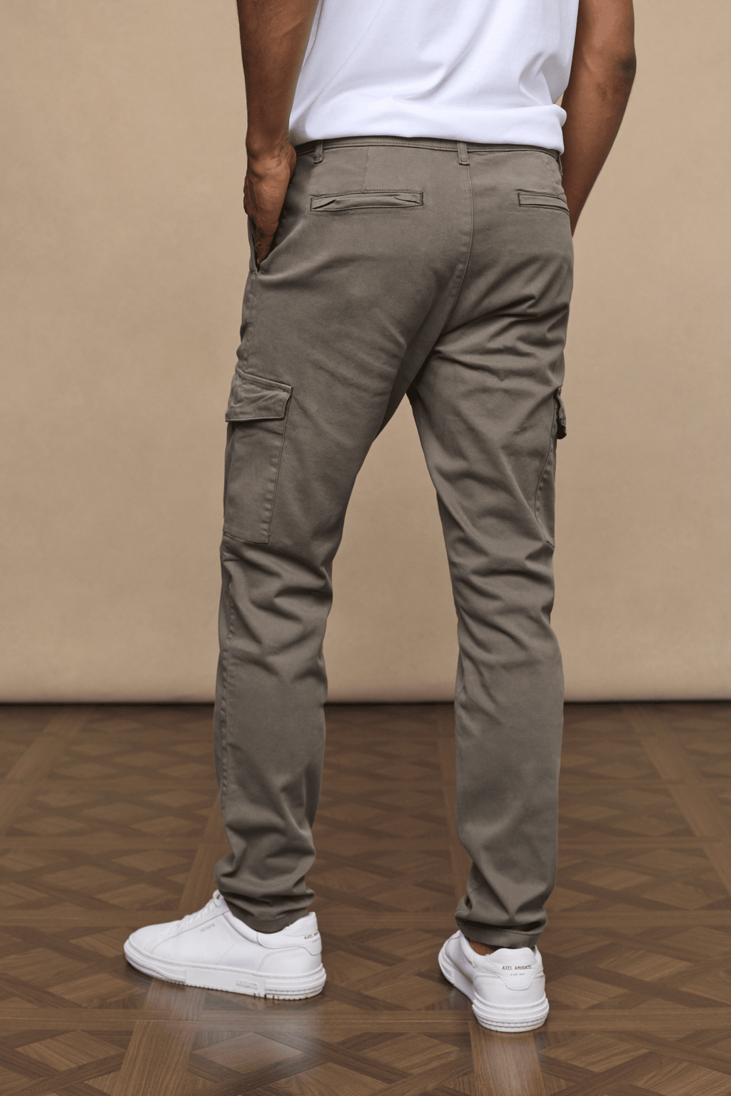 Man wearing dark olive Lenox Cargo pants with utility pockets, straight leg, and white sneakers.