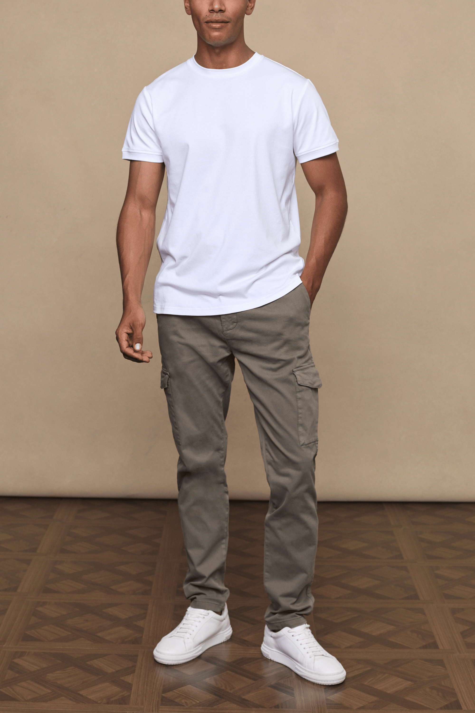 Man wearing dark olive Lenox Cargo pants with utility pockets, a white t-shirt, and white sneakers.