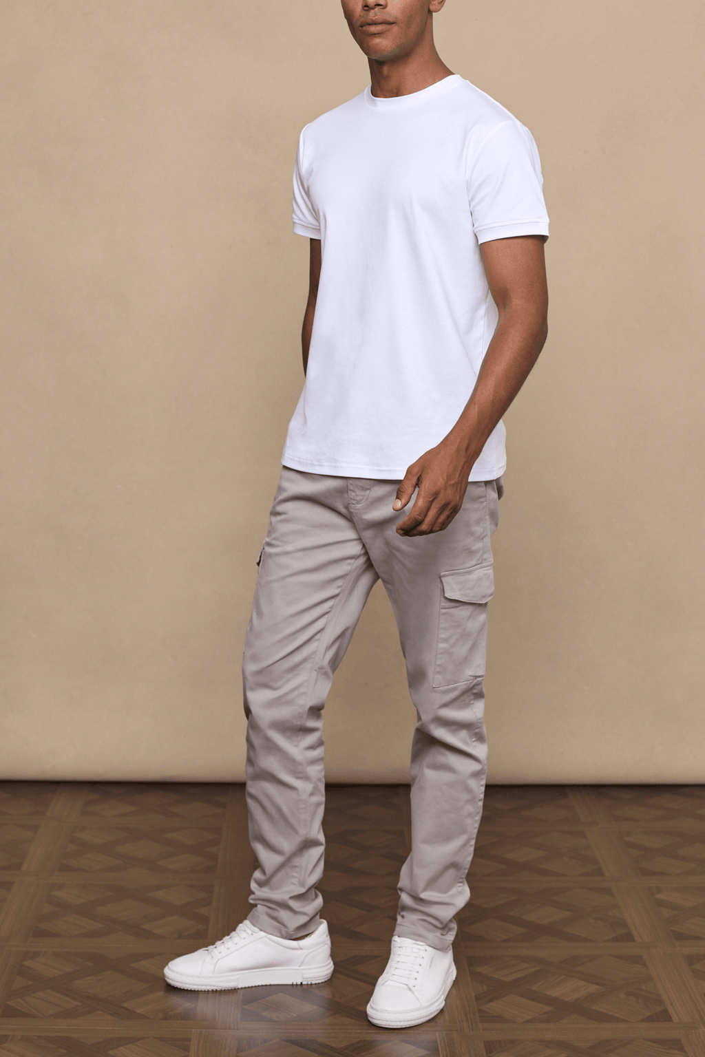 Man wearing Lenox Cargo pants in Greige with utility pockets, paired with a white t-shirt and white sneakers.