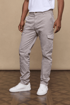 Men's Lenox Cargo Pant in greige cotton-elastane blend, straight leg, utility pockets, worn with white sneakers.