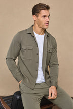 Man wearing a dark olive Leo overshirt with dual chest pockets over a white tee, paired with matching trousers.
