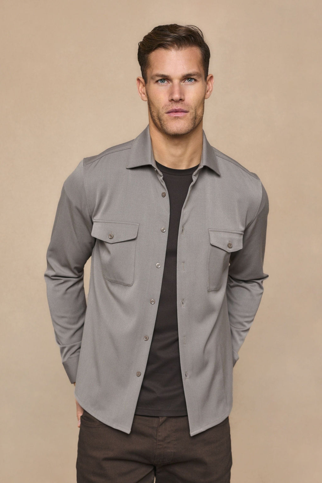 Man wearing a warm grey Leo overshirt with dual chest pockets over a dark t-shirt.