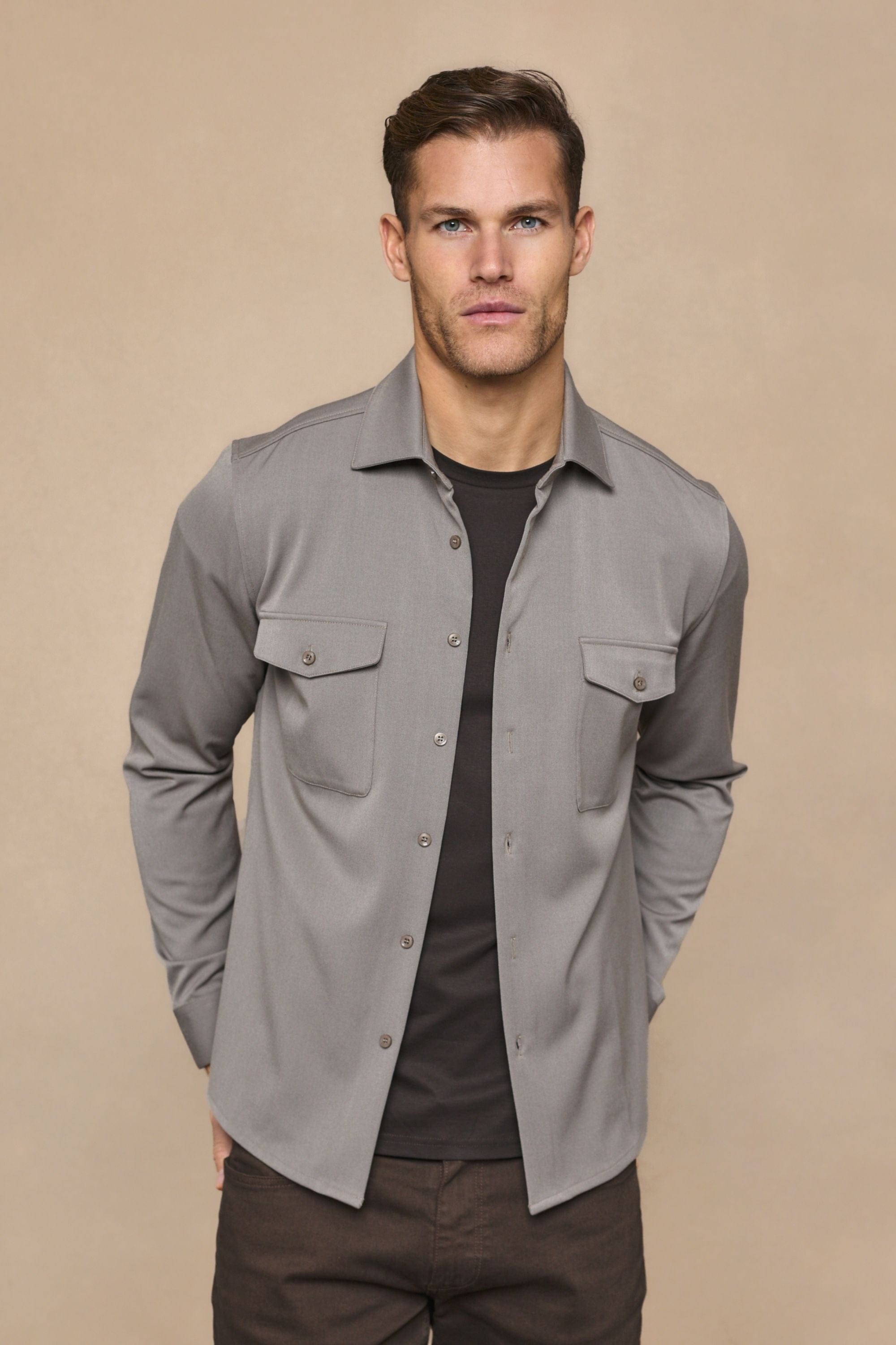 Man wearing a warm grey Leo overshirt with dual chest pockets over a dark t-shirt.