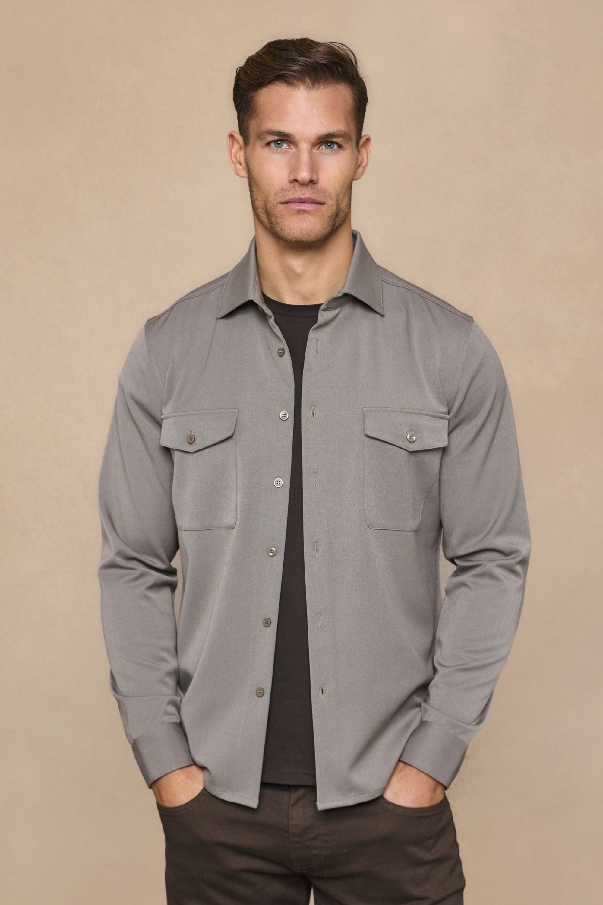 Man wearing a warm grey Leo overshirt with dual chest pockets over a black tee and dark pants.