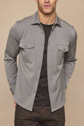Leo Overshirt in warm grey, soft stretchy fabric, with dual chest pockets and tonal buttons, worn over a black tee.