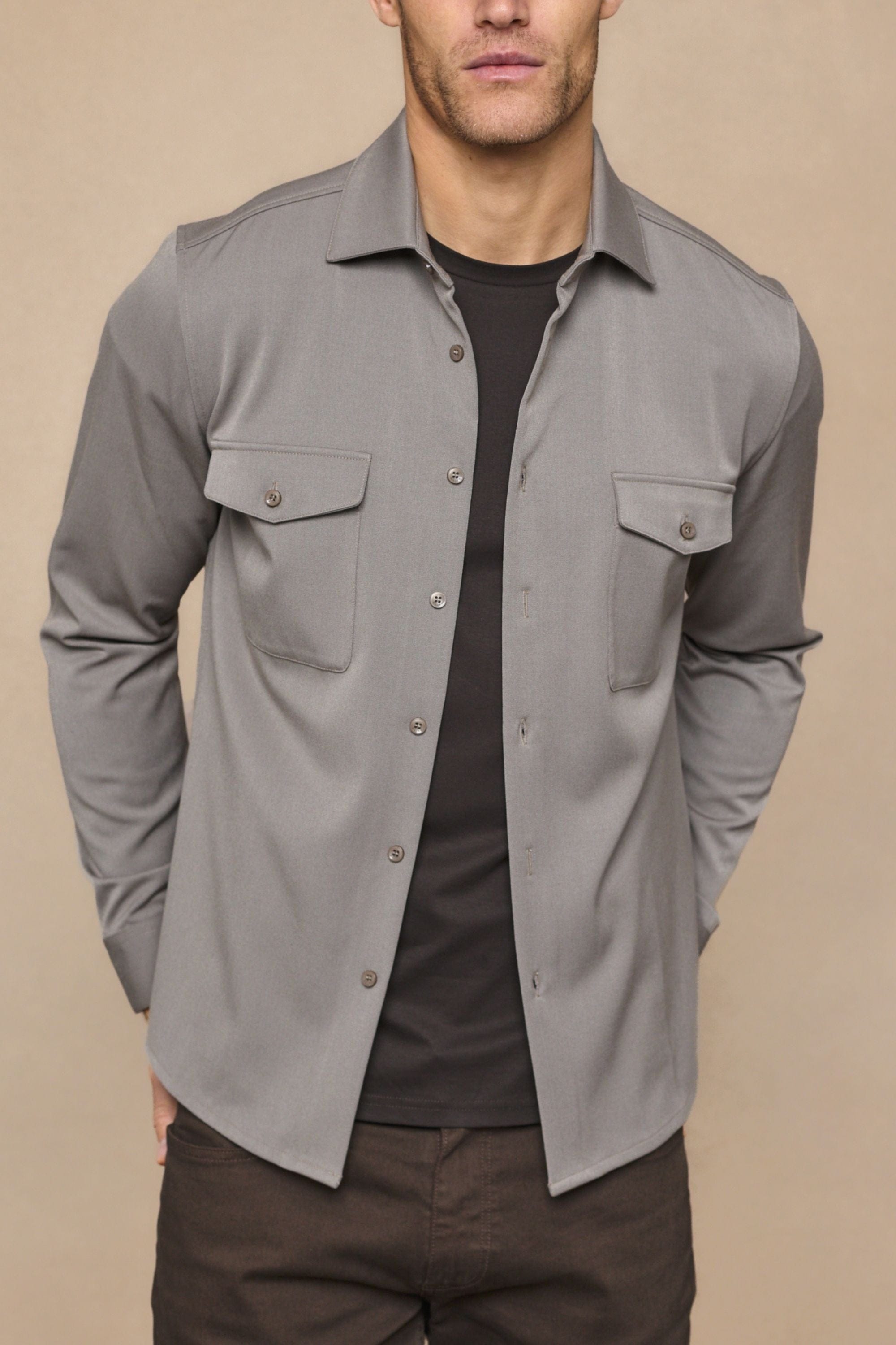 Leo Overshirt in warm grey, soft stretchy fabric, with dual chest pockets and tonal buttons, worn over a black tee.
