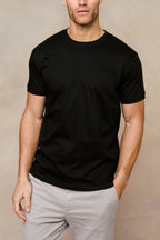 Man wearing a black mercerised cotton crew-neck t-shirt with light grey trousers.