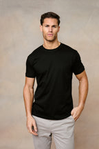 Man wearing a black Luxe Mercerised cotton crew-neck T-shirt with a subtle sheen and light grey chinos.