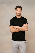 Man in a black Luxe Mercerised Cotton Crew-Neck T-Shirt with short sleeves, arms crossed.