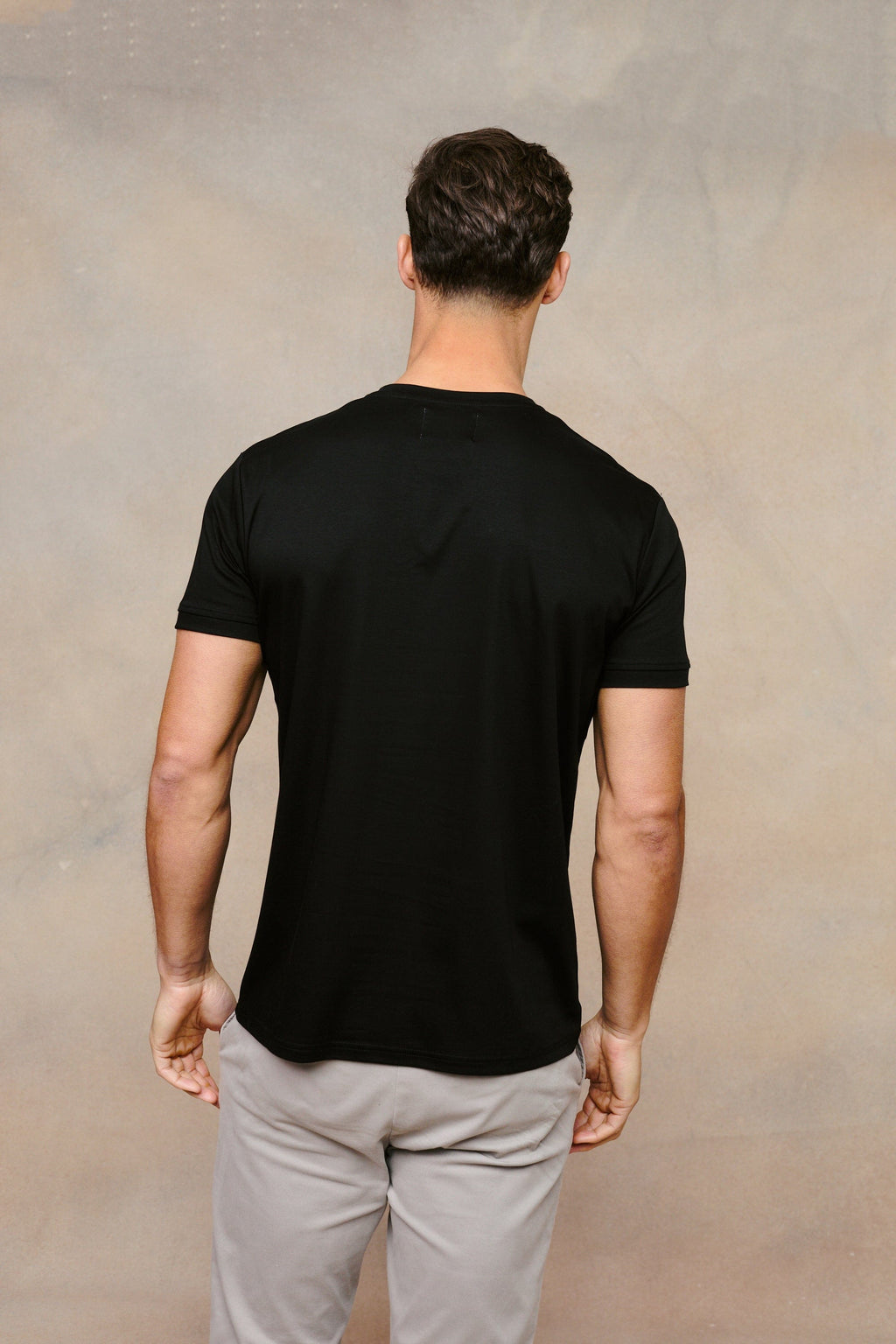Man from behind wearing a black mercerised cotton crew-neck t-shirt with a subtle sheen.