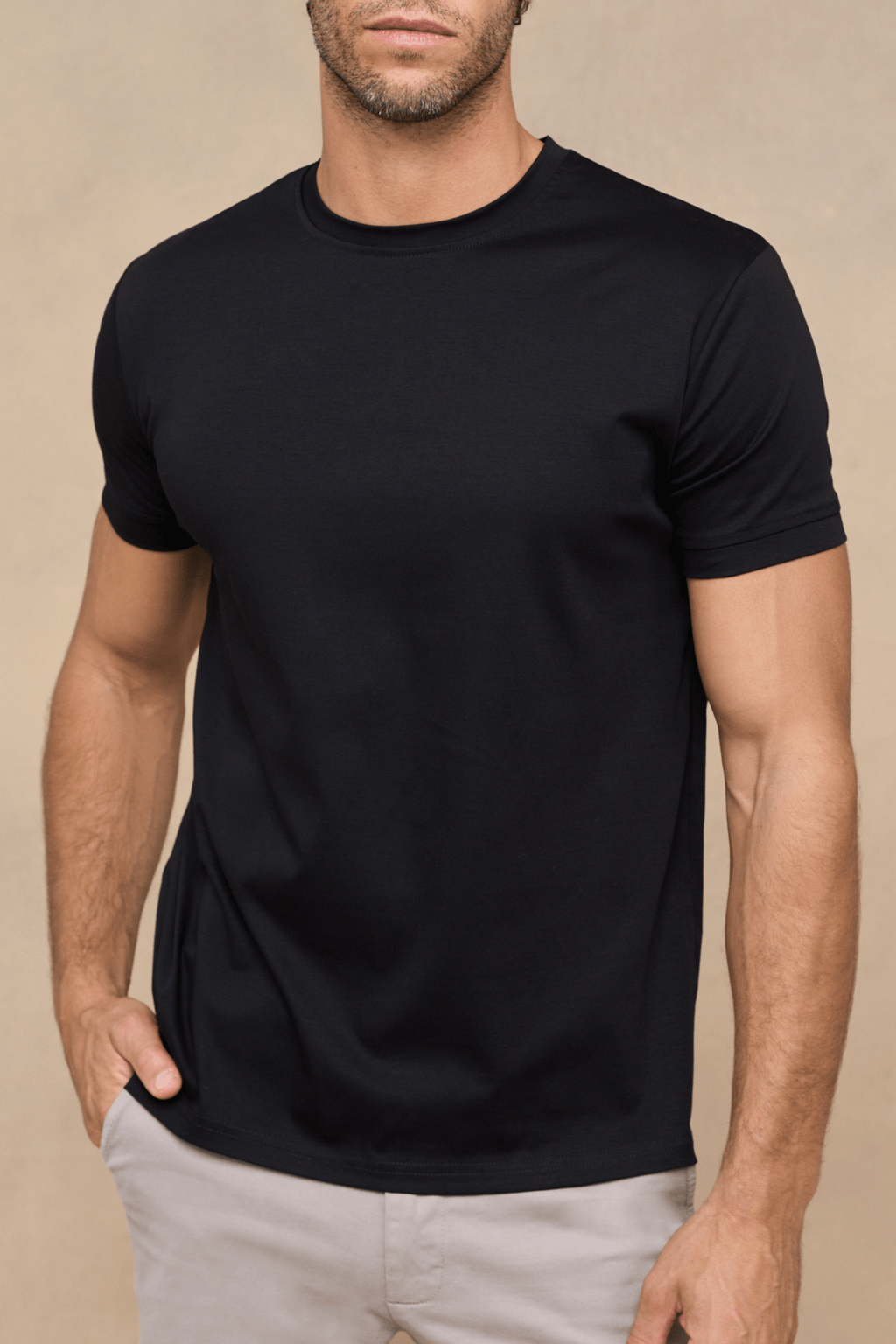 Man wearing a black mercerised cotton crew-neck t-shirt with a subtle sheen, paired with light trousers.