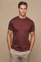 Man wearing a rust mercerised cotton crew-neck t-shirt with a subtle sheen and light beige trousers.