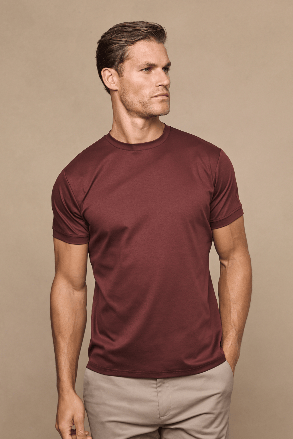 Man wearing a rust mercerised cotton crew-neck t-shirt with short sleeves and beige trousers.