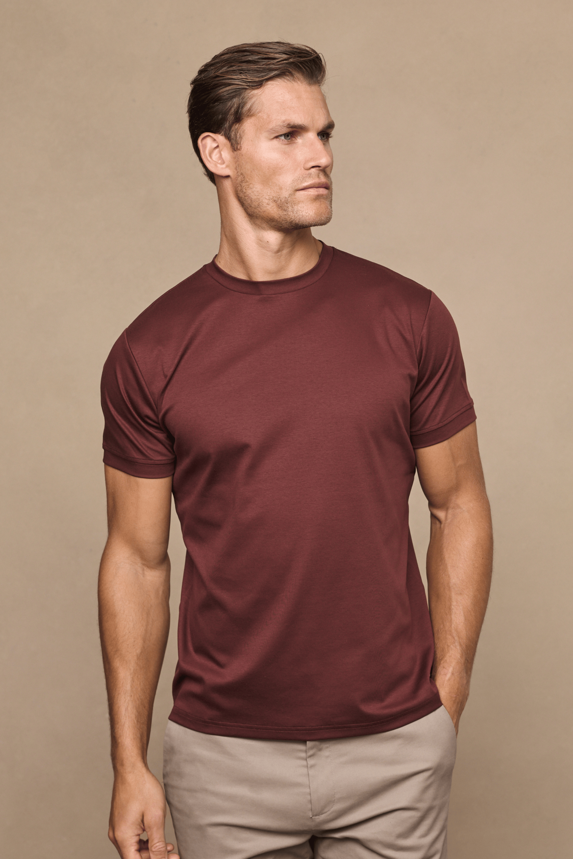 Man wearing a rust mercerised cotton crew-neck t-shirt with short sleeves and beige trousers.