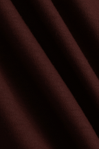 Close-up of rust mercerised cotton t-shirt fabric with subtle sheen and diagonal folds.