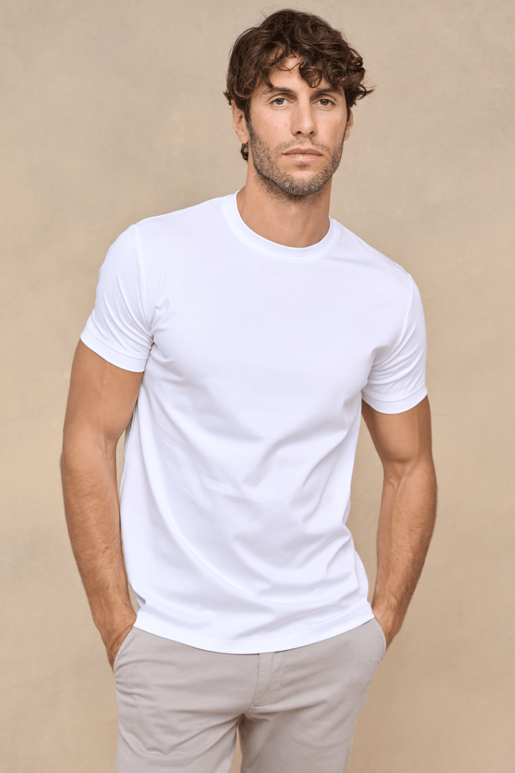 Man wearing a white mercerised cotton crew-neck t-shirt with a subtle sheen, paired with light grey trousers.