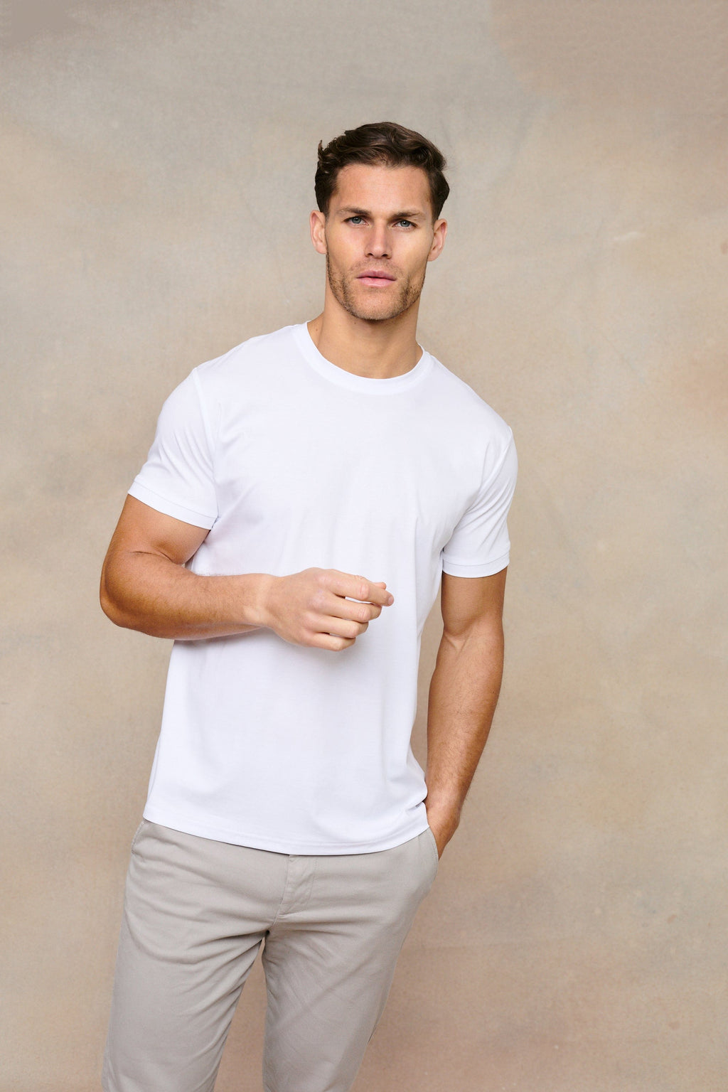 Man wearing a white mercerised cotton crew-neck t-shirt and light grey trousers.