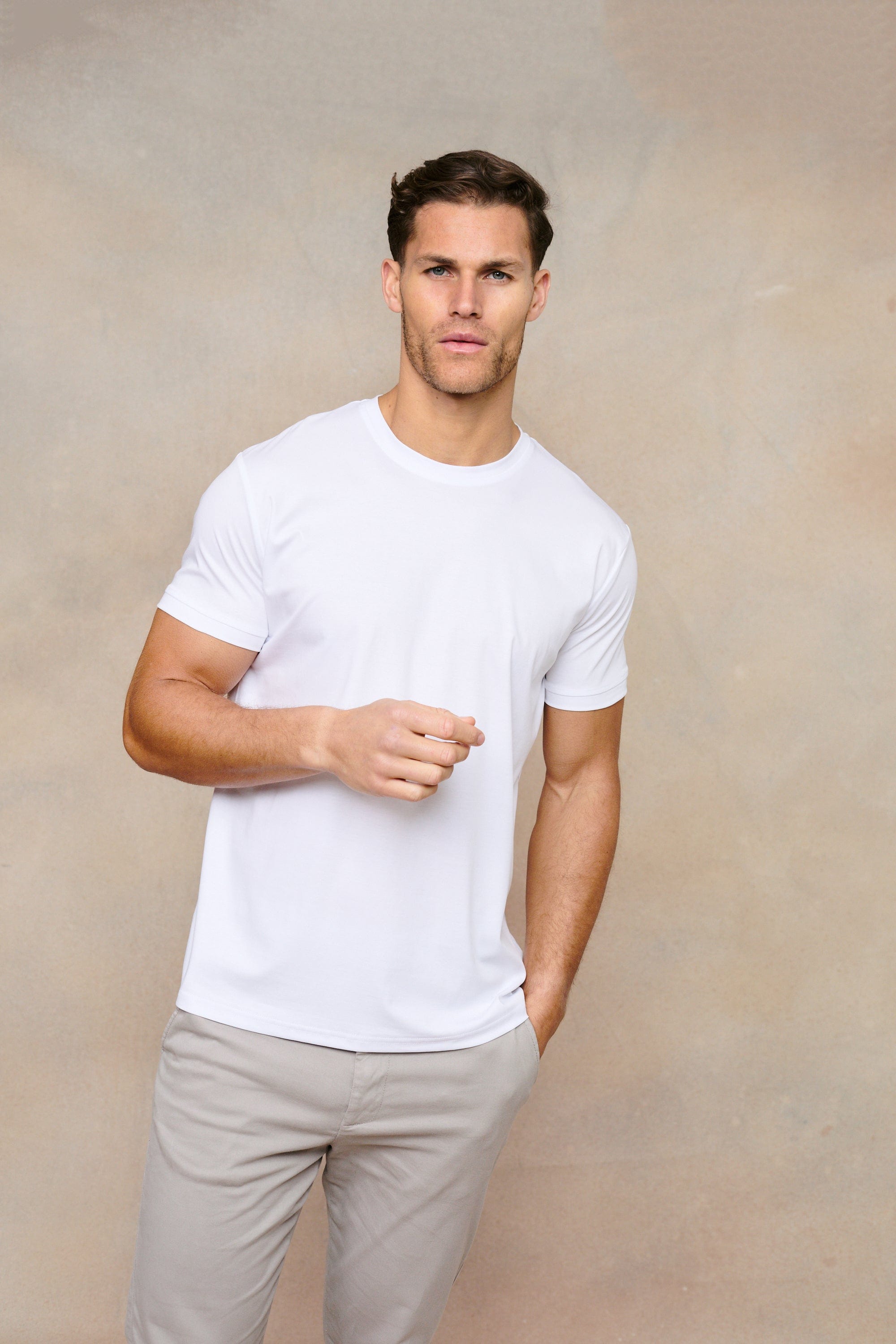 Man wearing a white mercerised cotton crew-neck t-shirt and light grey trousers.