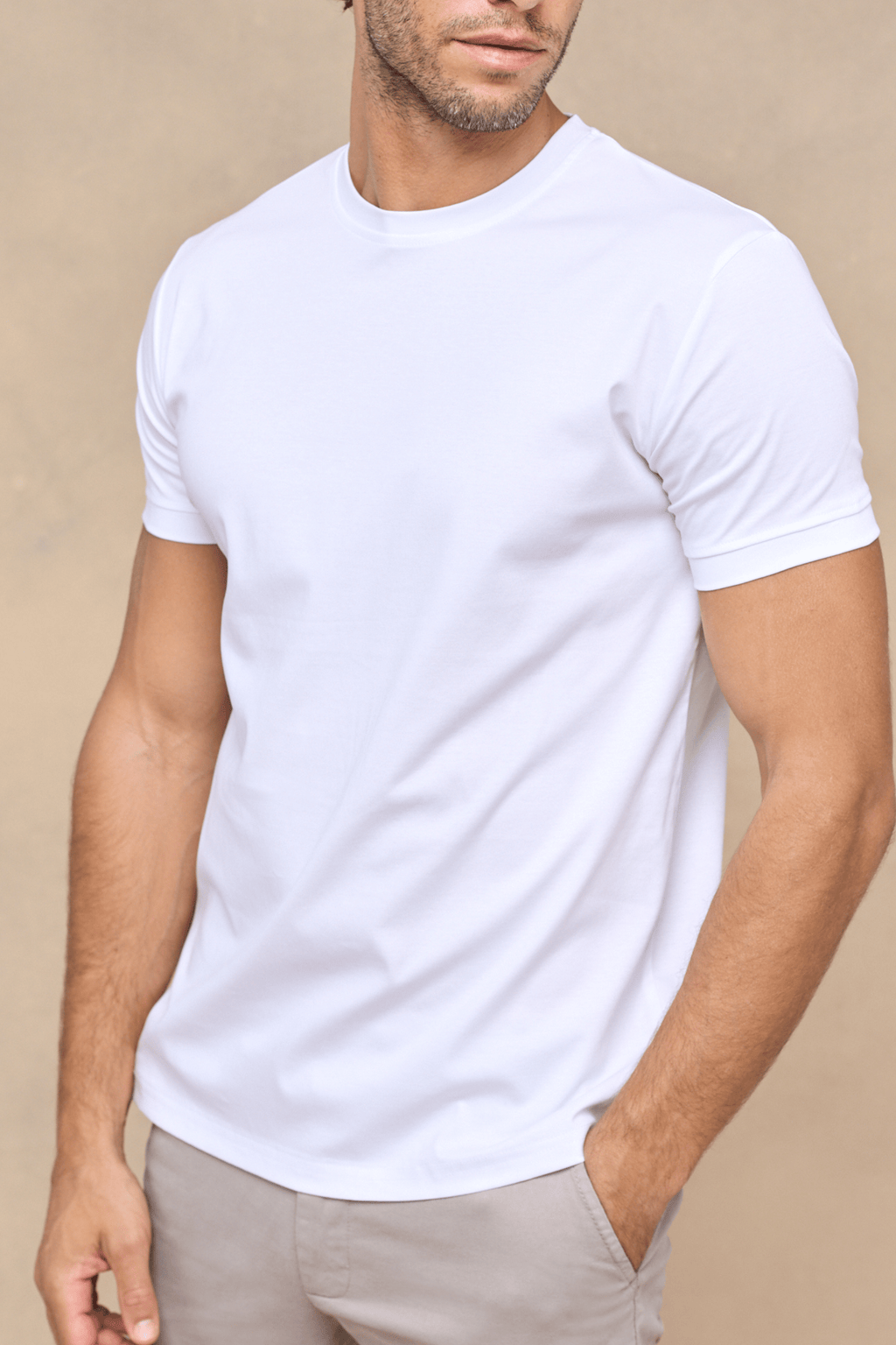 Man wearing a white mercerised cotton crew-neck t-shirt with short sleeves and light beige trousers.