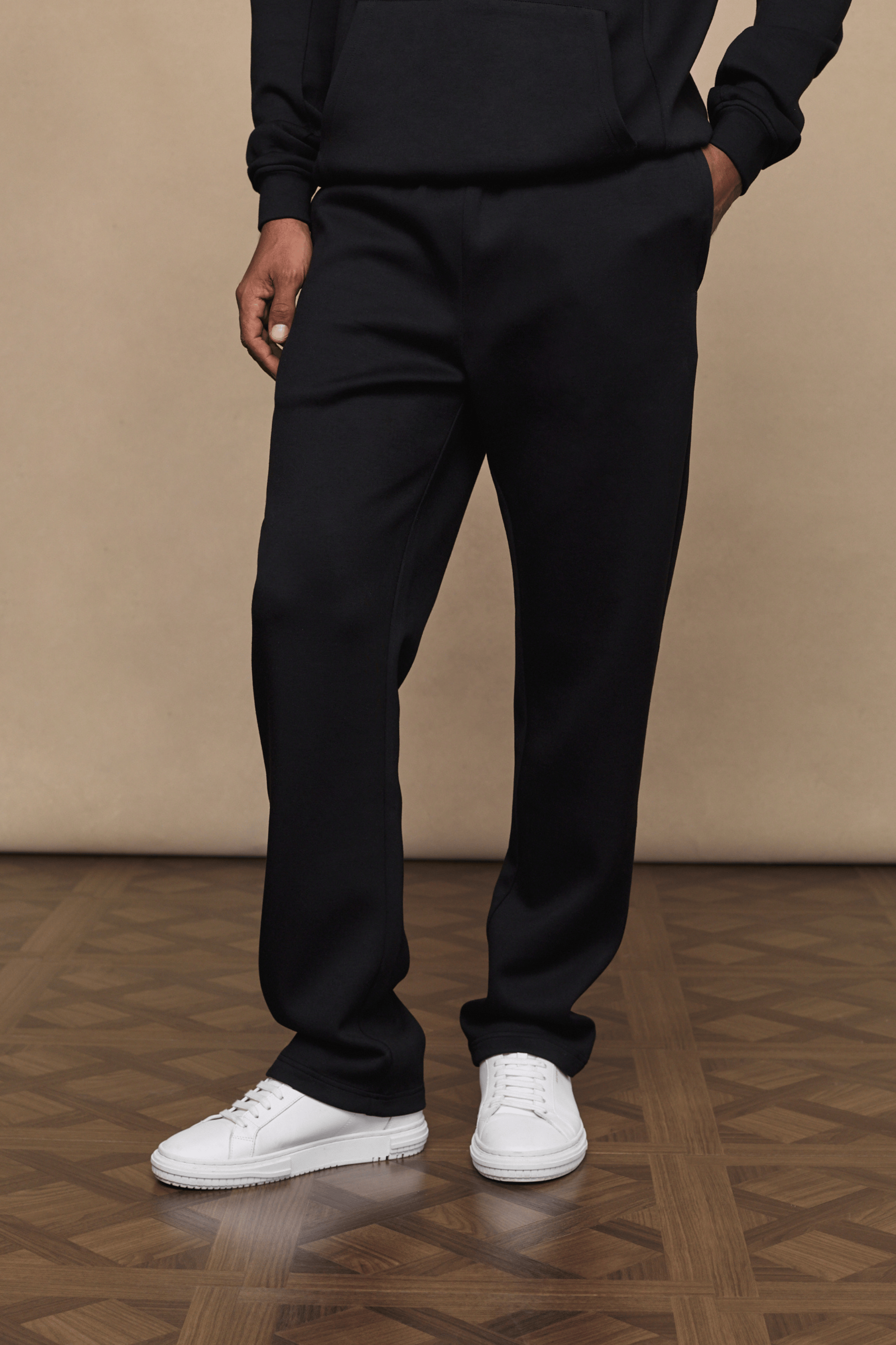 Black Luxe Straight Leg Jogger in soft fabric with subtle sheen, worn by a person with white sneakers.