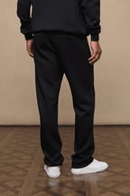 Black Luxe Straight Leg Jogger, 380gsm fabric, with side pockets and metal hardware, worn with white sneakers.