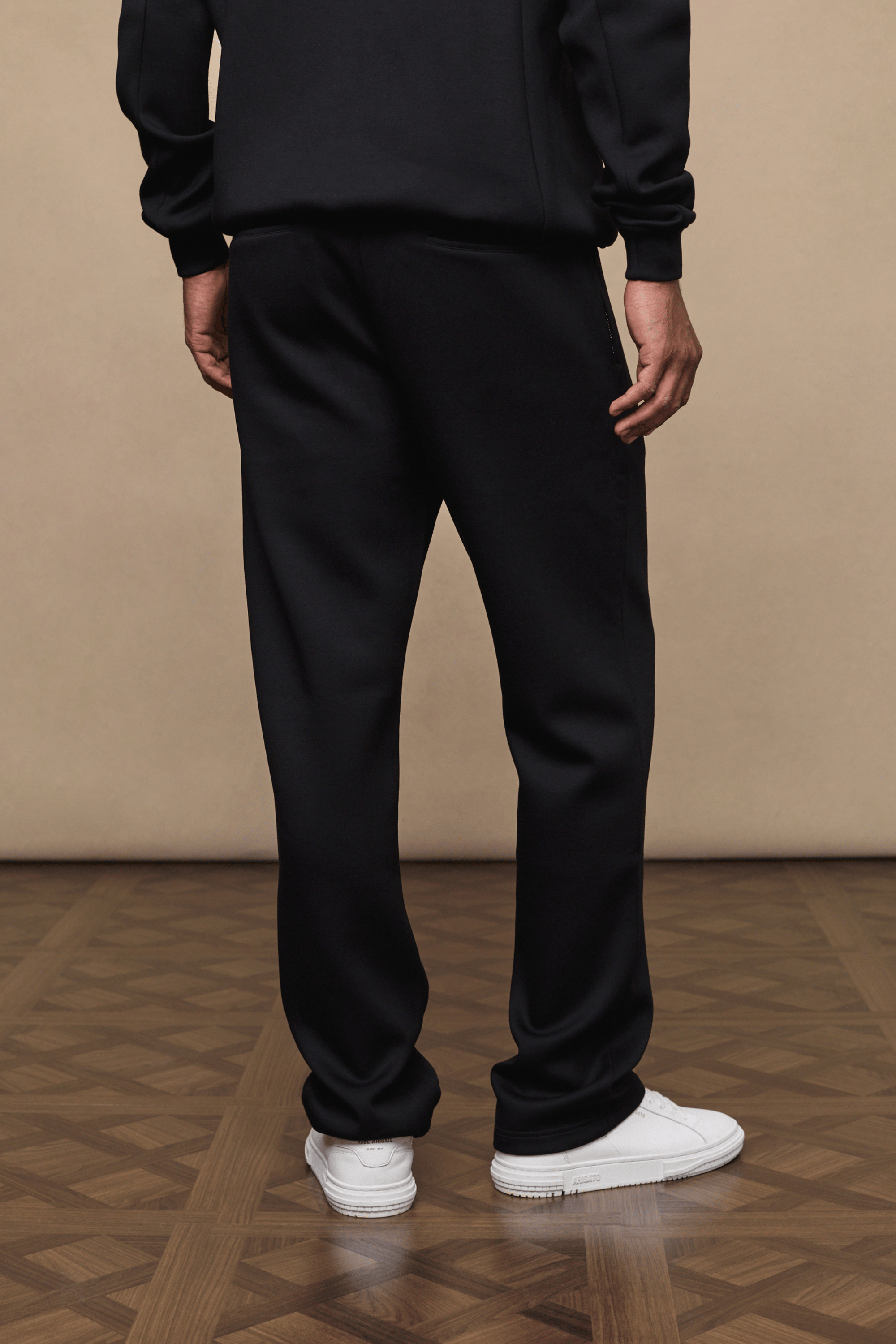 Black Luxe Straight Leg Jogger, 380gsm fabric, with side pockets and metal hardware, worn with white sneakers.