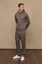 Man wearing a Luxe Straight Leg Jogger in Burnt Olive with a matching hoodie and white sneakers.