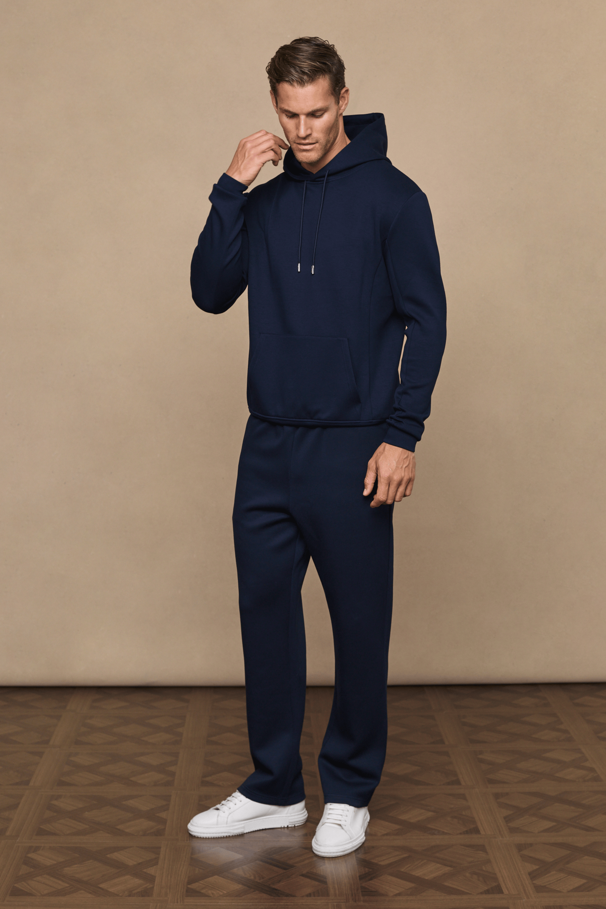 Man wearing a navy Luxe Straight Leg Jogger and matching hoodie, featuring a subtle sheen and clean silhouette.