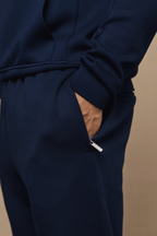 Navy Luxe Straight Leg Jogger with a hand in the side entry pocket, featuring a subtle sheen and metal hardware.