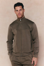 Man wearing a burnt olive Luxe Zip Through Jacket with metal hardware and matching pants.