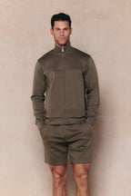 Man in Burnt Olive Luxe Zip Through Jacket and matching shorts, featuring metal hardware.