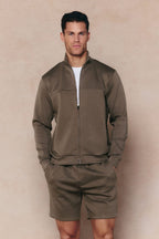 Man in burnt olive Luxe Zip Through Jacket and matching shorts, showcasing the premium fabric and paneled design.
