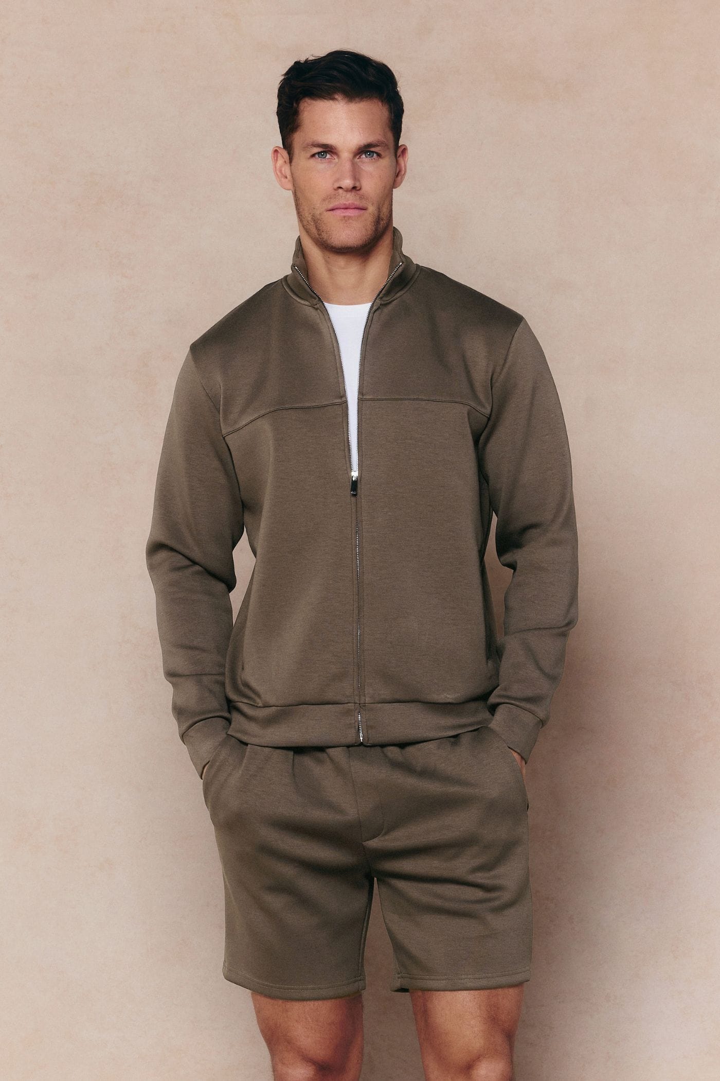 Man in burnt olive Luxe Zip Through Jacket and matching shorts, showcasing the premium fabric and paneled design.