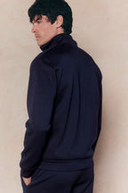 Man in a navy Luxe Zip Through Jacket, relaxed fit, soft stretchy fabric, with a high collar and ribbed cuffs.