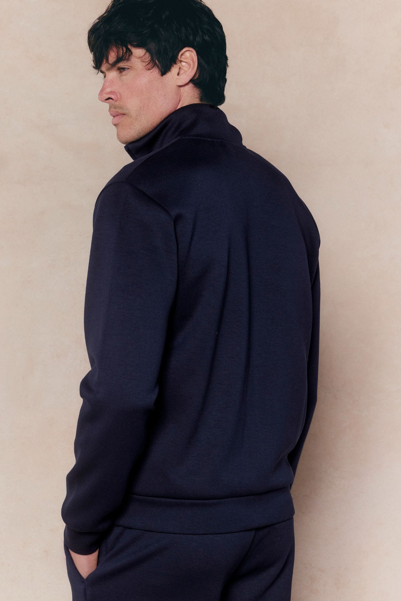 Man in a navy Luxe Zip Through Jacket, relaxed fit, soft stretchy fabric, with a high collar and ribbed cuffs.