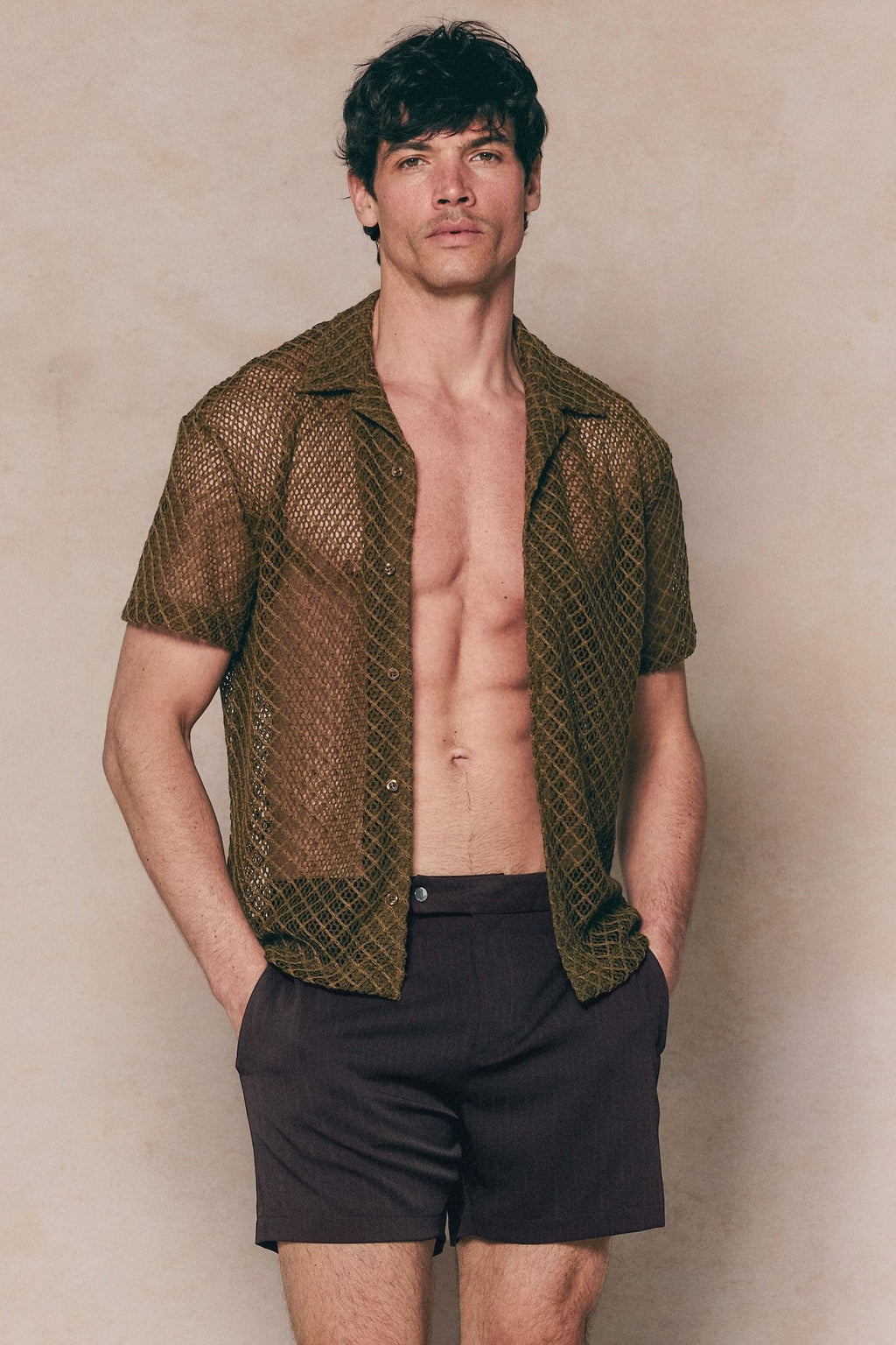 Man wearing a brown Marcelo short sleeve lace shirt, open over dark shorts.