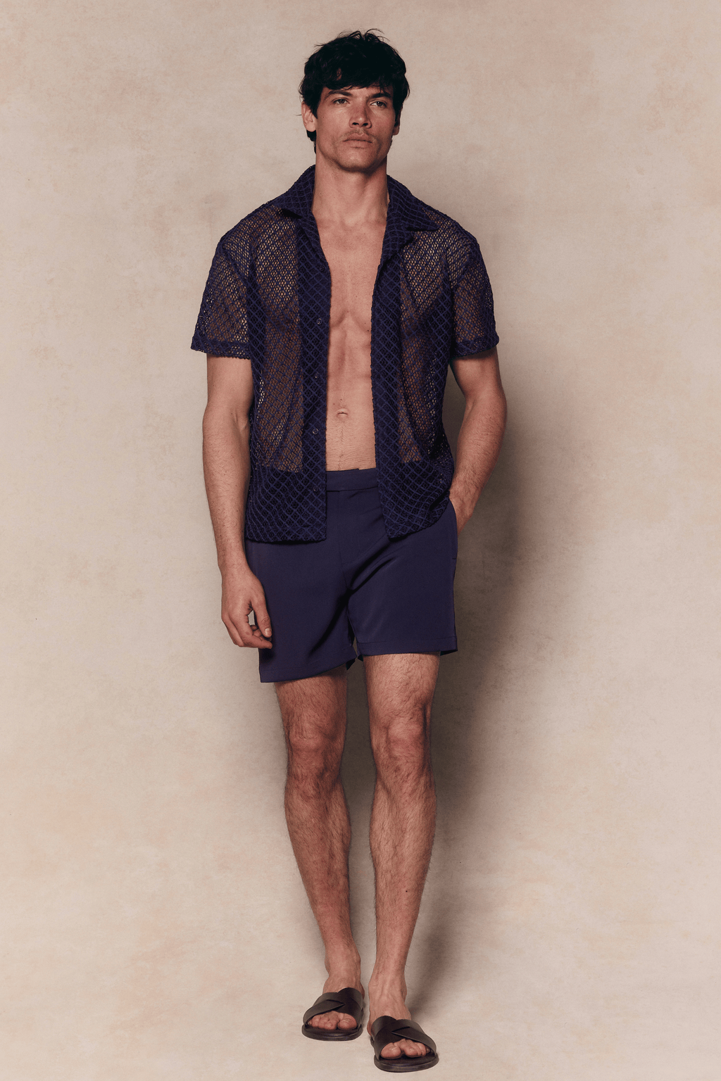 Man in a navy Marcelo short sleeve lace shirt and matching shorts, with an open, textured finish.