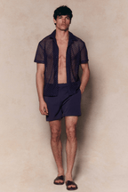 Man in a navy Marcelo short sleeve lace shirt and matching shorts, with an open, textured finish.