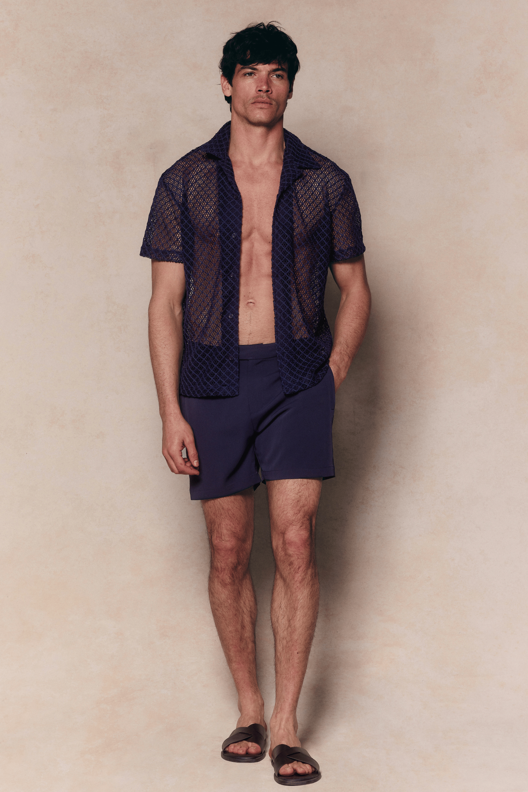 Man in a navy Marcelo short sleeve lace shirt and matching shorts, with an open, textured finish.