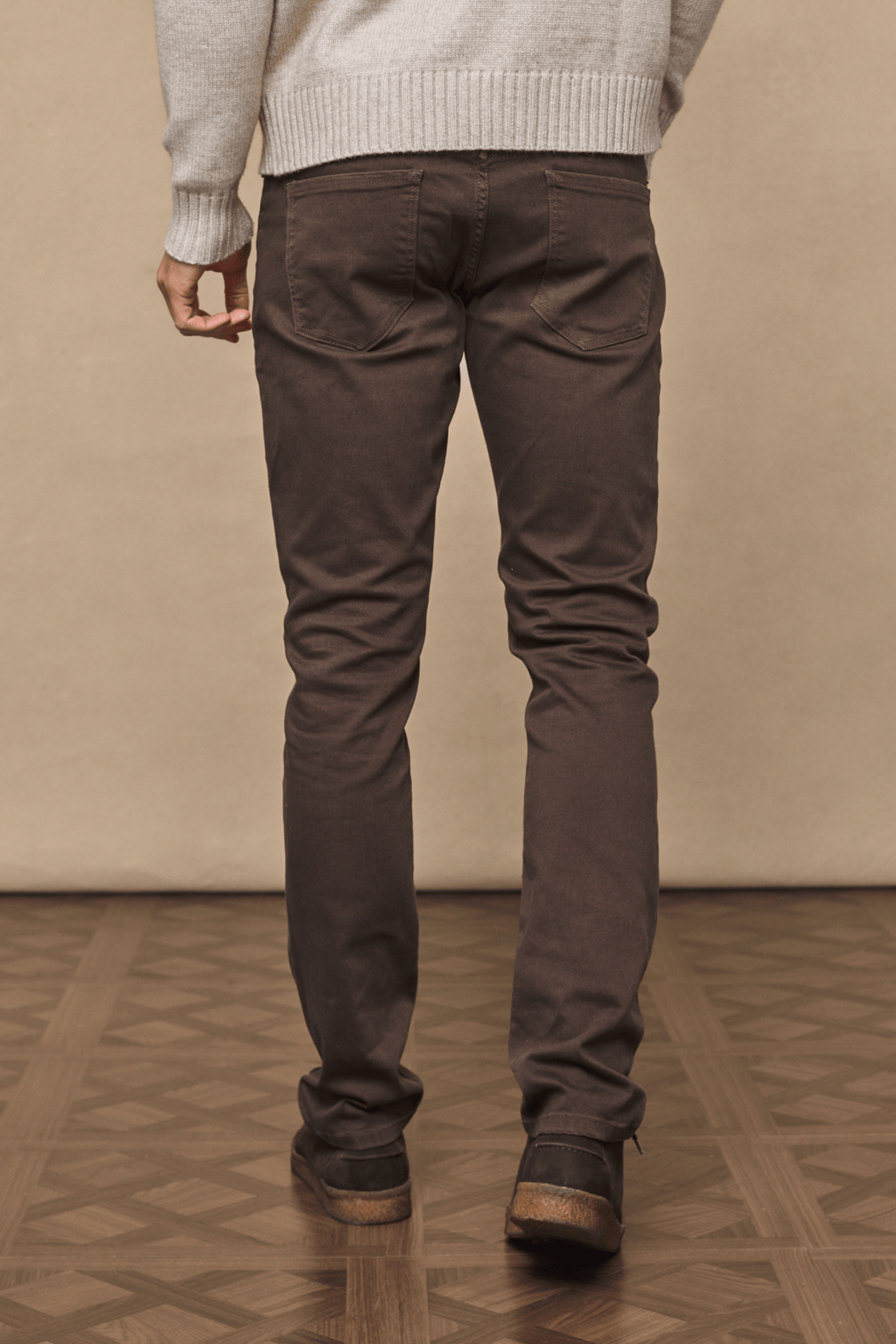 Man wearing dark brown Marco straight-slim jeans with a leather back patch and branded hardware.