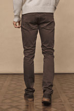 Man wearing dark brown Marco straight-slim jeans with a leather back patch and branded hardware.