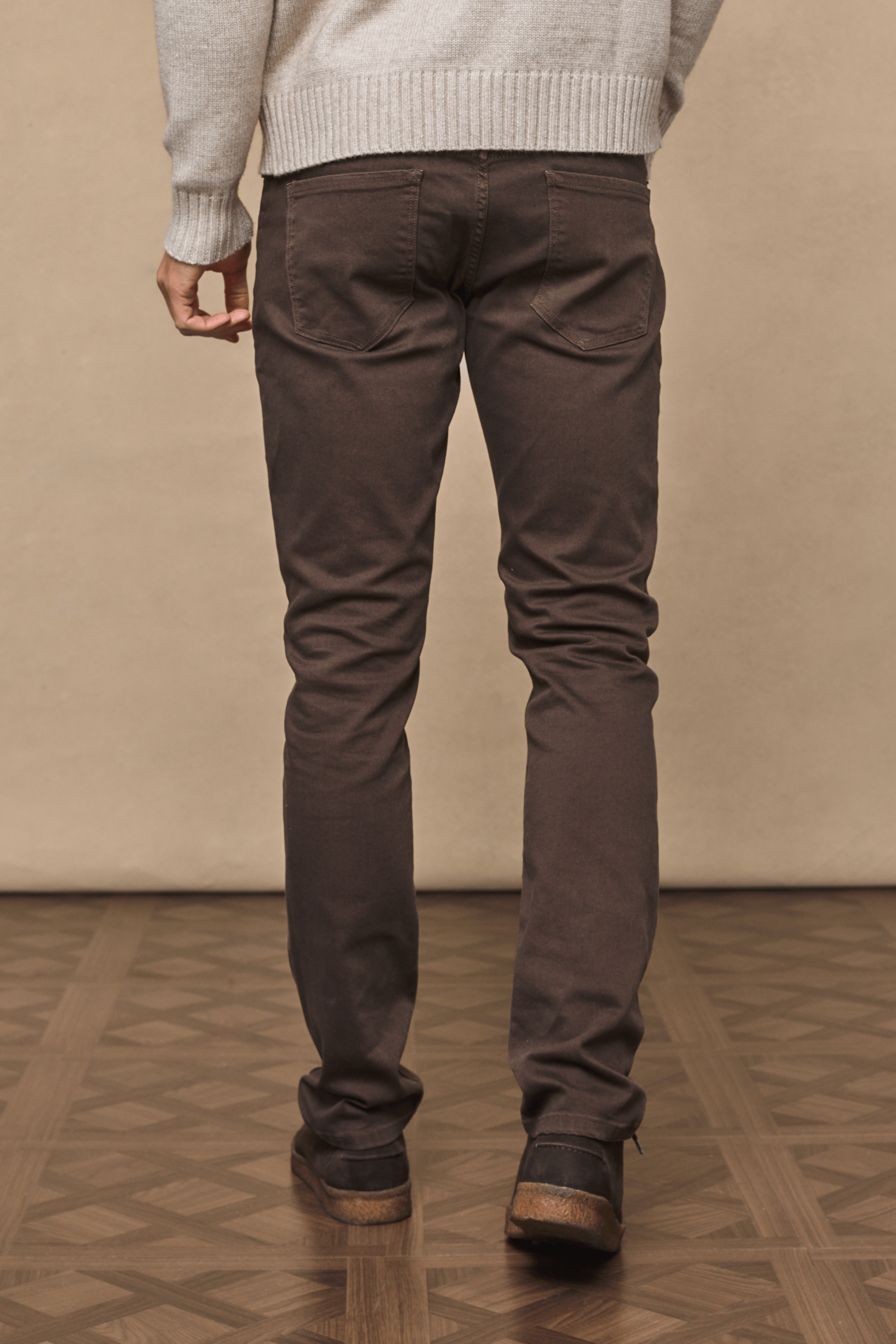 Man wearing dark brown Marco straight-slim jeans with a leather back patch and branded hardware.