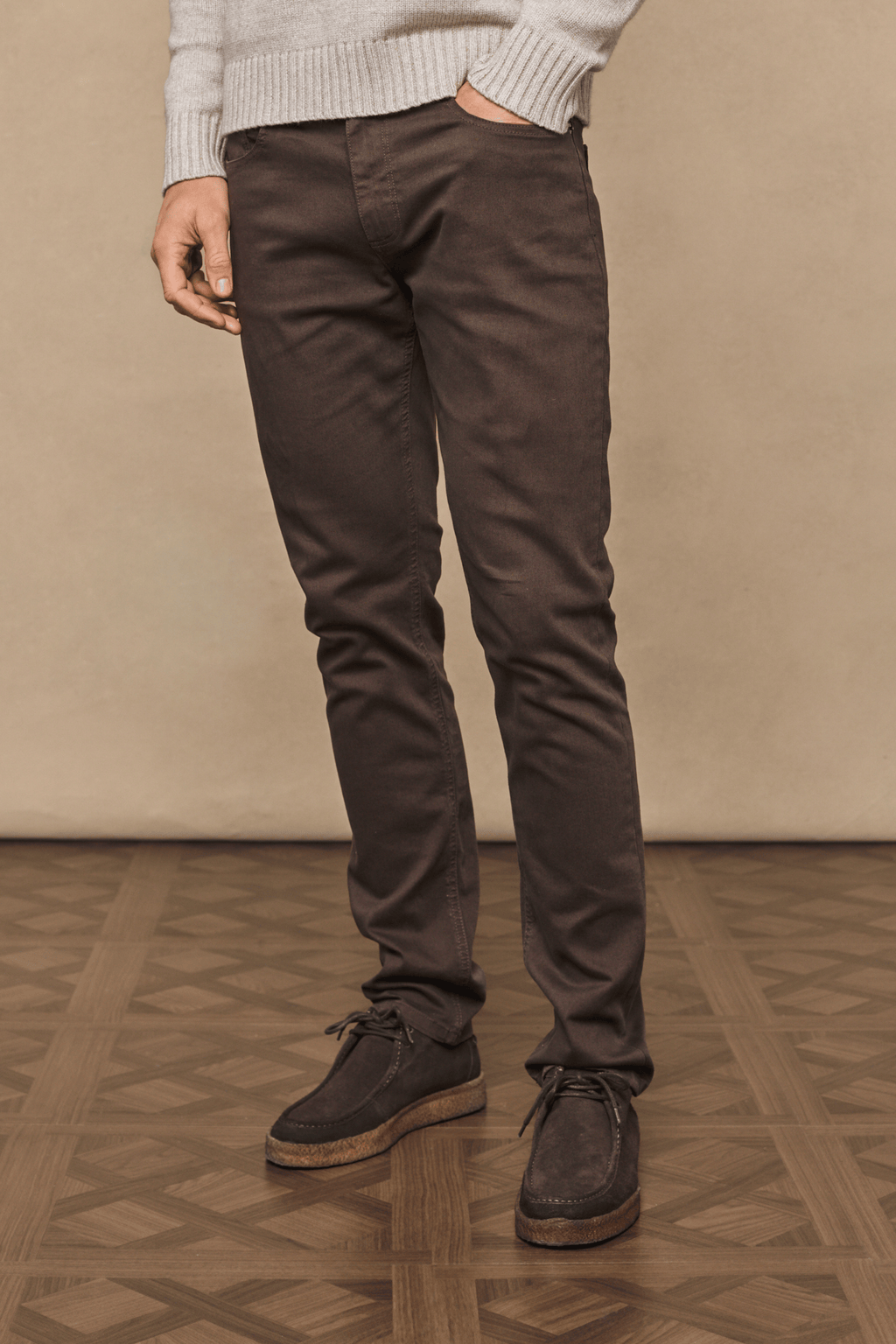 Man wearing dark brown Marco Jean, a straight-slim fit denim with a leather back patch, paired with brown suede shoes.