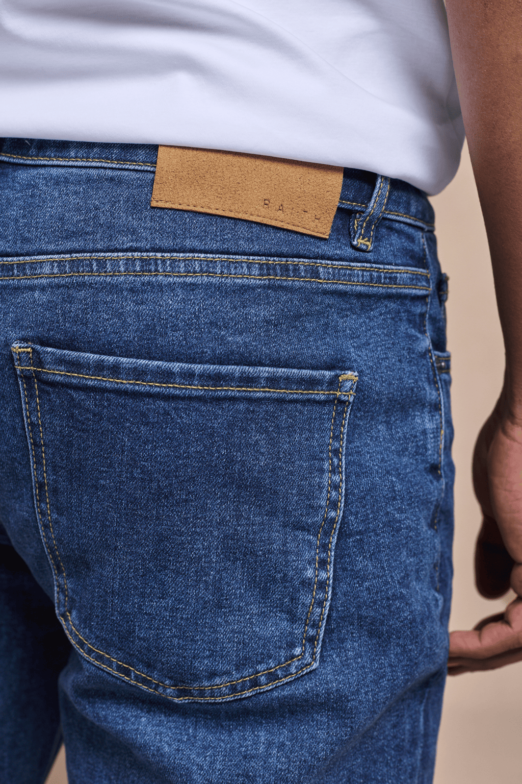 Marco Washed Jean in mid wash indigo, featuring a brown leather back patch and visible back pocket.