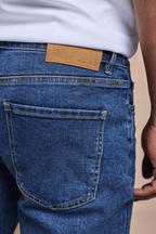 Marco Washed Jean in mid wash indigo, featuring a brown leather back patch and visible back pocket.