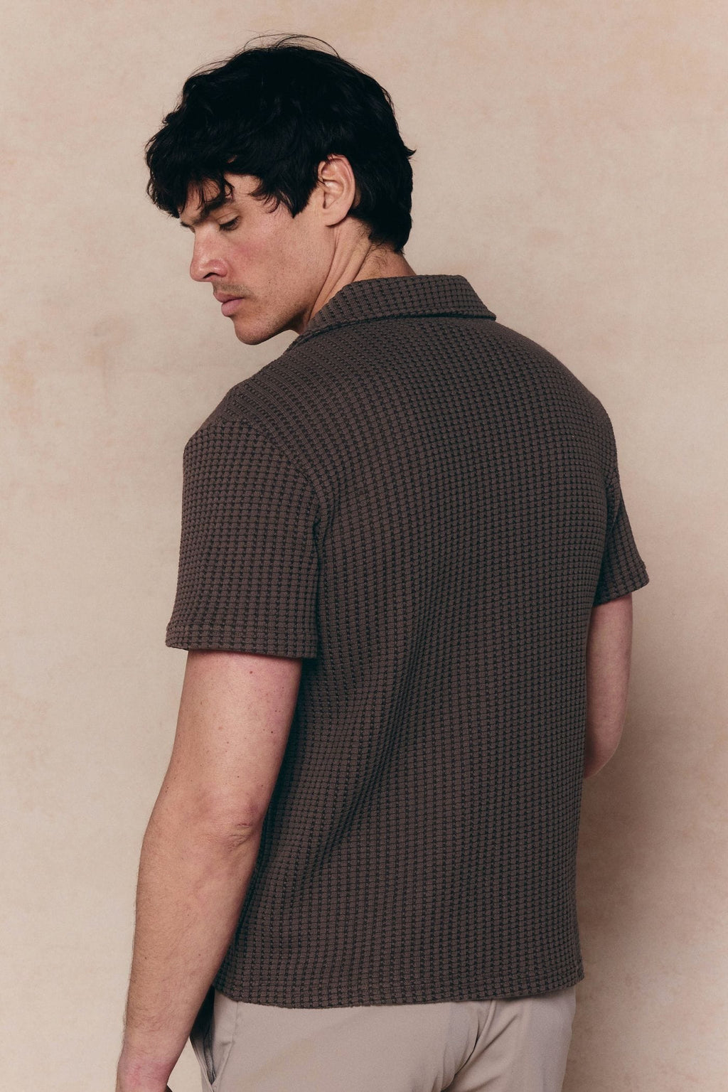 Man wearing a brown Marcos patterned waffle short sleeve shirt with an open collar.