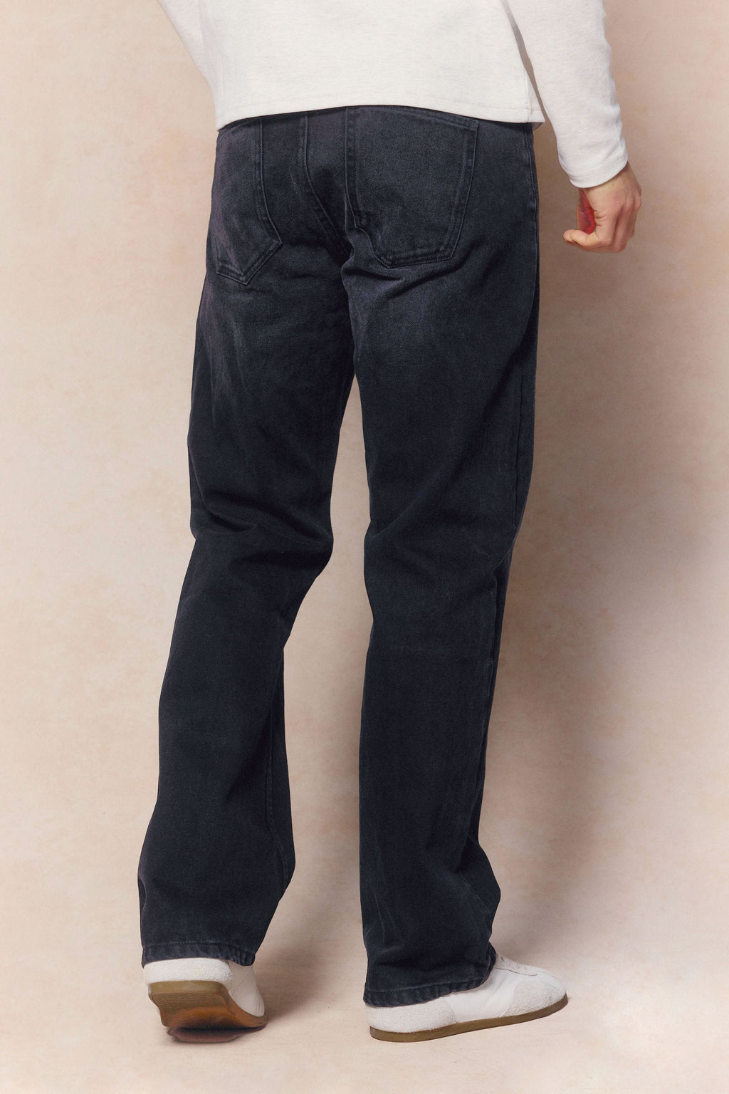Man wearing black wash Mason relaxed fit jeans made from 14oz cotton denim, featuring a leather back patch.