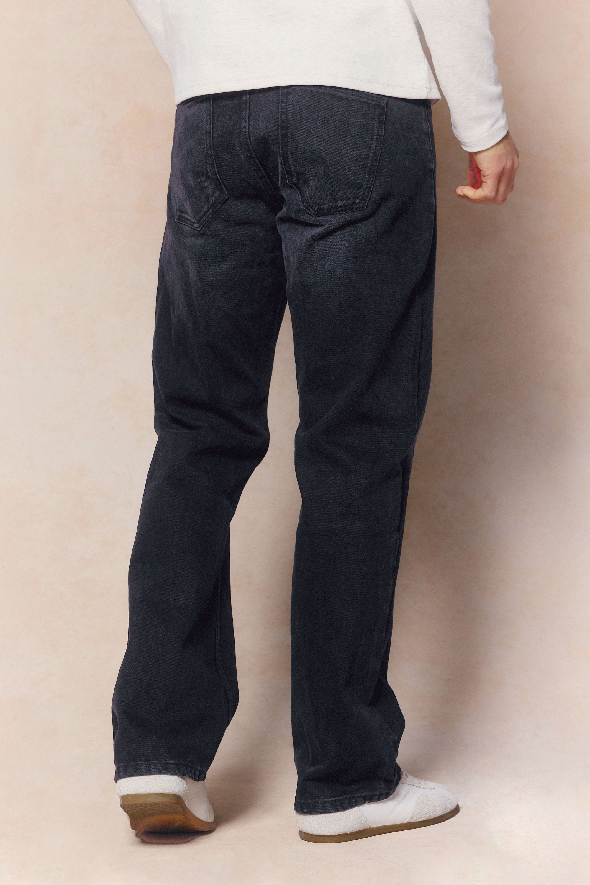 Man wearing black wash Mason relaxed fit jeans made from 14oz cotton denim, featuring a leather back patch.