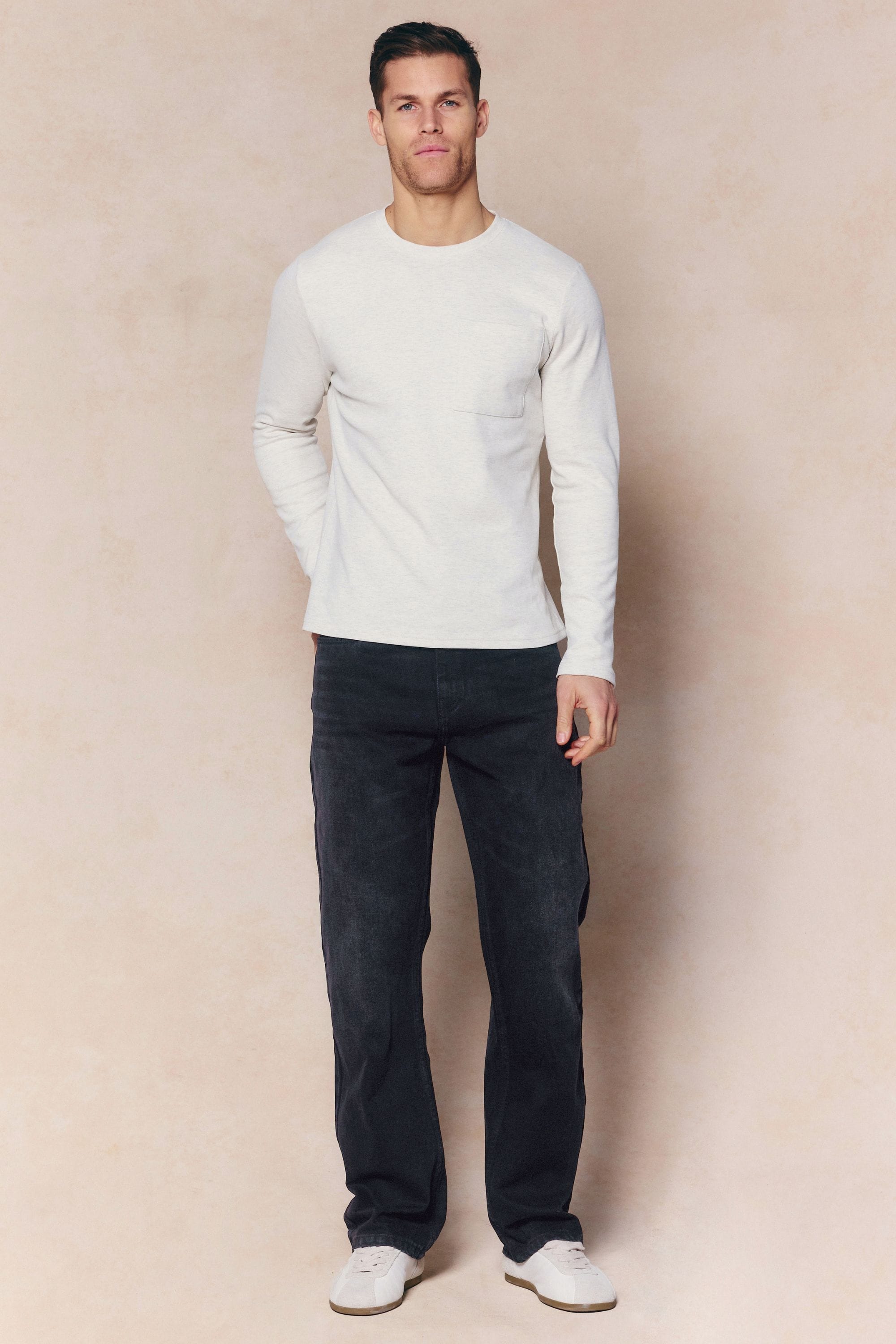 Man wearing black wash Mason Relaxed Fit Jeans and a light long-sleeve shirt.